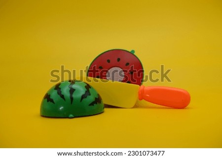 toy watermelon, knife and plate isolated on yellow background. Watermelon toys that can be installed and removed.