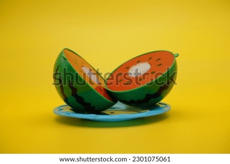 toy watermelon and plate isolated on yellow background. Watermelon toys that can be installed and removed.