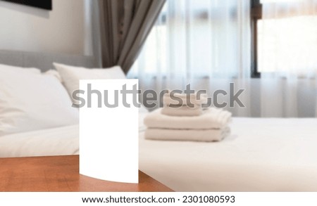 White sign cardboard with copy space on a white round table. Hotel interior. Empty white card on a card holder in a hotel room