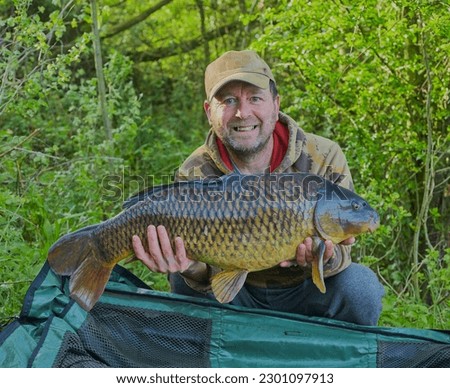 Fisherman holding a common carp up for a picture.