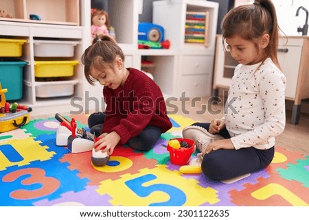 Adorable girls playing supermarket game sitting on floor at kindergarten