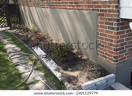 Picture view of a smooth, fresh cement parging application technique used to coat a damaged concrete house foundation. Thin coating that can help protect the wall from moisture and weather damage.