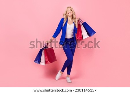 Full size portrait of gorgeous cheerful girl hands hold boutique bags isolated on pink color background