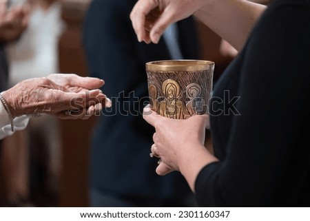 Receiving hands in position to take the Eucharistic Communion bread in Catholic church ceremony. Royalty-Free Stock Photo #2301160347