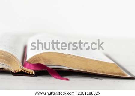 Closeup of open holy bible book with gold pages isolated on wooden table with white background. Copy space. Christian Scripture Study, biblical concept. Royalty-Free Stock Photo #2301188829