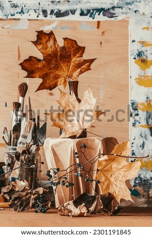Still life with artistic brushes, autumn leaves, artist's palette and picture frame. Autumn mood and inspiration