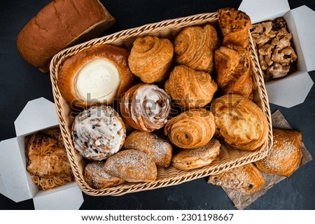 Cafe menu, breakfast basket. Fresh pastries: croissants, rolls, puffs and bun with sour cream in basket with chicken and pasta in paper boxes. Top view. Royalty-Free Stock Photo #2301198667