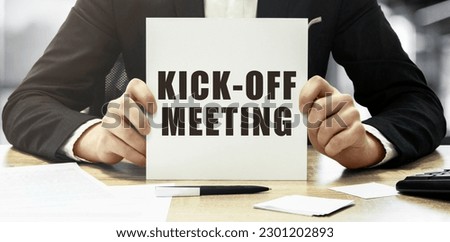 Businessman holding a white card with text Kick off meeting on office background Royalty-Free Stock Photo #2301202893