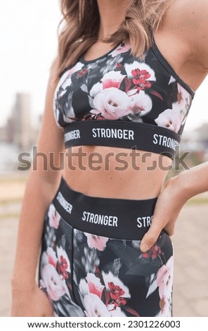 Stylish young fit athletic woman wearing a black floral workout set, blonde hair, city, Baltimore skyline, fashion, sitting on steps, downtown, happy, carefree, working out, work out