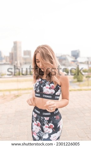 Stylish young fit athletic woman wearing a black floral workout set, blonde hair, city, Baltimore skyline, fashion, sitting on steps, downtown, happy, carefree, working out, work out