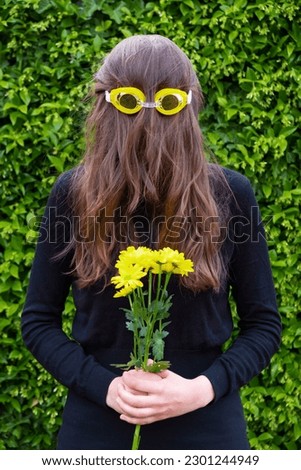 Claim photo in relation to climate change of an anonymous woman in a black mourning dress with flowers and yellow pool glasses on a green background. Climate change protest.
