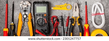 Electrician tools on black marble background.Multimeter,construction tape,electrical tape, screwdrivers,pliers,an automatic insulation stripper, socket and LED lamp.Flatley.electrician concept. Royalty-Free Stock Photo #2301247757