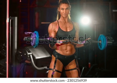 Bodybuilder woman, athlete with barbell make fitness exercises at the gym.