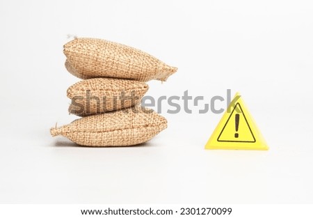 A picture of miniature grain bags with warning sign. Caution of shortage food supply concept.