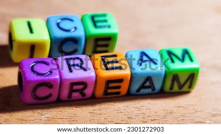 The word ICE CREAM is written in colorful plastic cuboid letters on a wooden background.