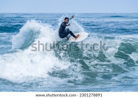 Surfer riding waves in Furadouro Beach, Portugal. Men catching waves in ocean. Surfing action water board sport. people water sport lessons and beach swimming activity on summer vacation. Royalty-Free Stock Photo #2301278891