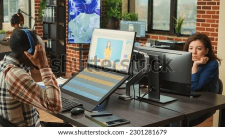 Young content creator retouching photos with color grading, using touchscreen monitor and stylus. Image editor with graphic tablet using editing software to retouch picture in agency studio.