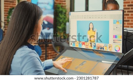 Female colorist editor using retouching software with tablet, working on multimedia production in agency office. Asian worker editing photos and pictures with touchscreen display and stylus.