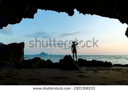 silhouette of a girl at sunset on the coast framed by rocks
