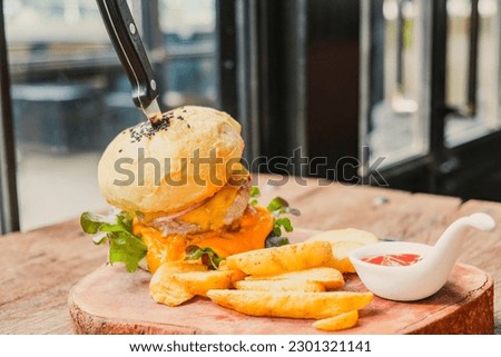 Burgers and potato chips complemented with ketchup on a wooden tray, American-style, elegant and appetizing in a vintage-style restaurant.