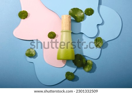 Concept of natural cosmetics with gotu kola extract - green bottle display on abstract background with fresh gotu kola leaves. Copy space