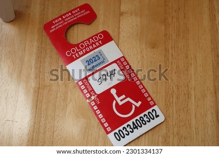 Red handicapped Colorado car permit placard for parking in designated spaces. Hangs from the rear view mirror. Display when parked in reserved parking spots. Expiration date and rules.