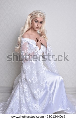 Close up portrait of beautiful women with long blonde hair, wearing white fantasy princess ball gown,  white studio background with wallpaper texture.
