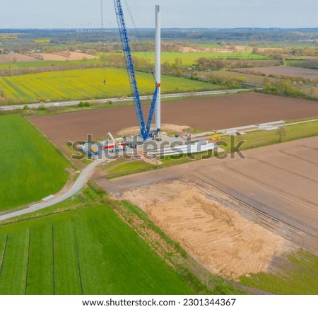 Construction of a wind turbine with a blue crawler crane Royalty-Free Stock Photo #2301344367