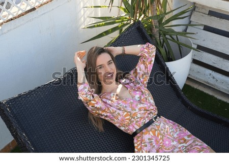Beautiful young blonde woman lying on a sun lounger on the rooftop of her house in Spain. The woman is enjoying the day and sunbathing.