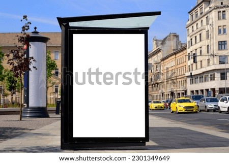 bus shelter blank ad panel. billboard display. empty white lightbox sign at bus stop. glass structure. transit station. mockup base. urban street with traffic. park setting. bus shelter advertising