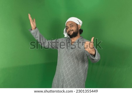 Young Indian farmer smiling and looking at camera, left hand thumbs up sign, isolated on green background, green screen, copy space