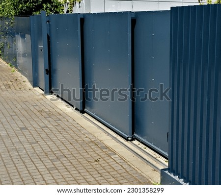 metal fillings of the fence with an underlay of concrete blocks. A metal aluminum fence will provide privacy around the garden. horizontal slats cover well.  made concrete block brick protection Royalty-Free Stock Photo #2301358299