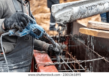 Mixer truck is transport concrete to the casting place on building site. selective focus. Concrete is flowing into the foundations of the building. Monolithic concrete works. Vibration of concrete Royalty-Free Stock Photo #2301361895