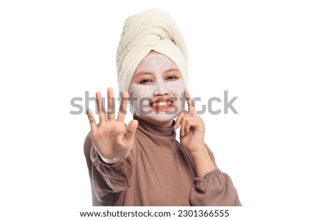 Closeup beauty skin care concept. Young woman applying white mask to face. beautiful woman after bath with towel on her head smiling cream on face isolated white background.