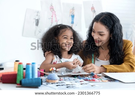 Dressmaker mom teaching her little daughter sewing, mother and daughter spend happily together Royalty-Free Stock Photo #2301366775