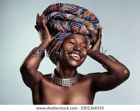 Beauty, black woman and laughing with African turban and smile in a studio. Isolated, grey background traditional makeup with a young female model with culture crown and fashion with cosmetics Royalty-Free Stock Photo #2301368335