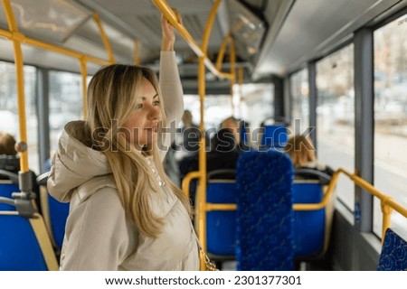 Beautiful young adult caucasian woman stands in the bus and looks into the distance Royalty-Free Stock Photo #2301377301