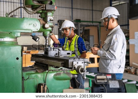 Asian engineer and worker operating lathe grinding machine - metalworking industry concept. Mechanical Engineering control lathe machine in factory. Royalty-Free Stock Photo #2301388435