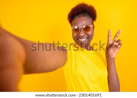 Young african american woman isolated on a yellow background smiling and making a selfie, studio shoot