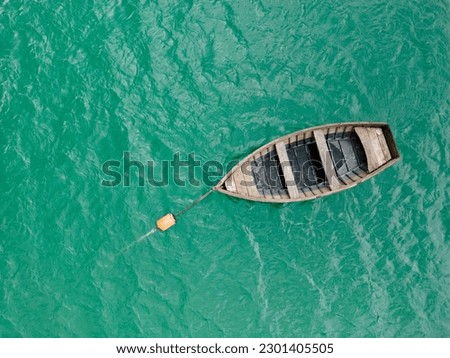 A picture-perfect top view of a tranquil lake with a wooden boat creating ripples on its surface.