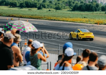 people from the stands watching the yellow drag car race