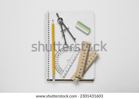 Protractor ruler, compass, pencil and notebook on white background, top view