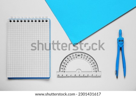 Protractor ruler, paper sheet, notebook and compass on white background, flat lay