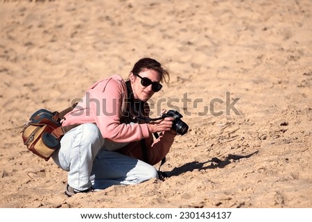 Woman with camera taking pictures on the beach in the evening