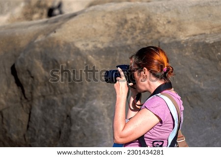 Woman with camera taking pictures on the beach in the evening