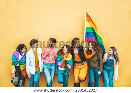 Diverse group of young people celebrating gay pride festival day - Lgbt community concept with guys and girls hugging together outdoors - Multiracial trendy friends standing on a yellow background  Royalty-Free Stock Photo #2301452027