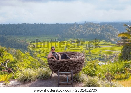 Beautiful Woman is sitting on a large bird nest in the jungle near the rice terraces -  Bali island, Indonesia