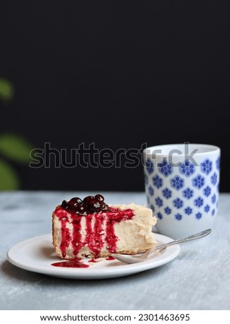 Slice of cheesecake with berry sauce on white plate. Homemade cheesecake with blackcurrant jam on top. Sweet food close up photo. Space for text. 