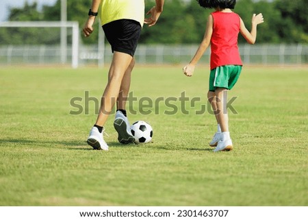 The picture shows only the lower half of the torso. of boys and girls Brother and sister who are having fun running and play football together in the green grass and enjoying their morning exercise.