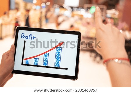 Business growth predication graph in Tablet with blur background of department store. Business successful concept. Concept of growth planning and strategy.